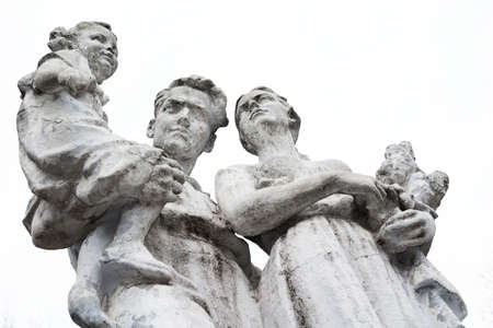 weathered old stone statue of family with children. Isolated on white backgroundの写真素材