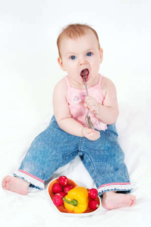 cute little girl playing with big spoon. Isolated on white backgroundの写真素材
