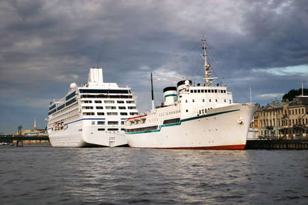 Ocean liners at St. Petersburg's port in the summer evening. Clouded skies and calm water.の写真素材