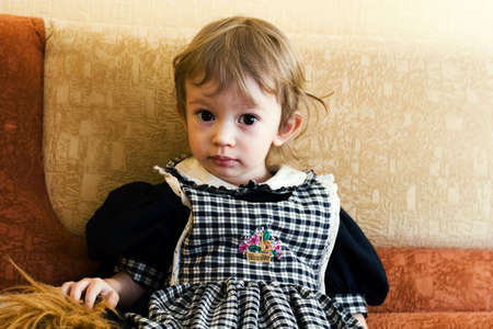 little cute girl sitting on the sofa. Special yellow toned photo f/xの写真素材