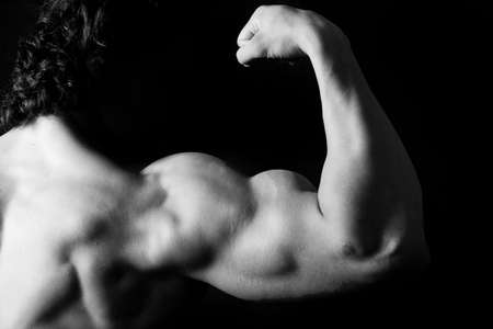 strong arm of young bodybuilder. Black and white photo on black backgroundの写真素材