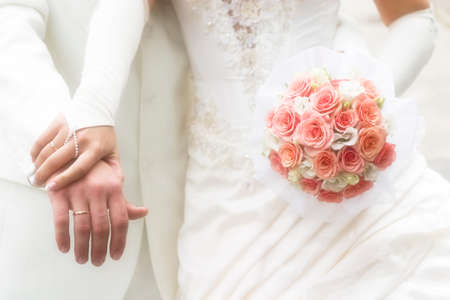 just married - young couple in wedding wear with bouquet of roses. Soft-focused image in high keyの写真素材