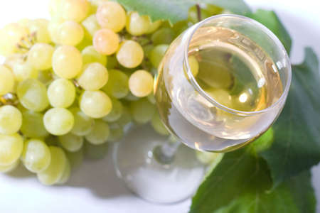 glass of white wine and white grapes. Low DOF, focal point is on wine