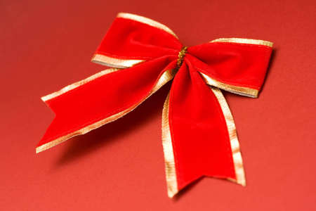 Red christmas bow on red textured cardboardの写真素材