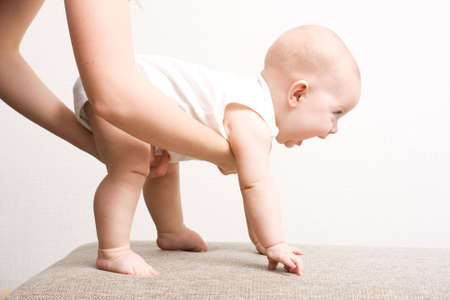 Cute baby trying to move with mother's hands support
