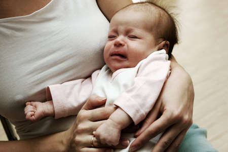 Crying cute newborn in the hands of mother