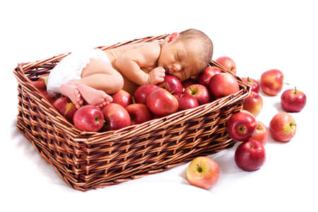 Newborn sleeping in the basket with applesの写真素材