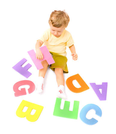 Cute little boy learning alphabet playing with letters. Isolated over whiteの写真素材