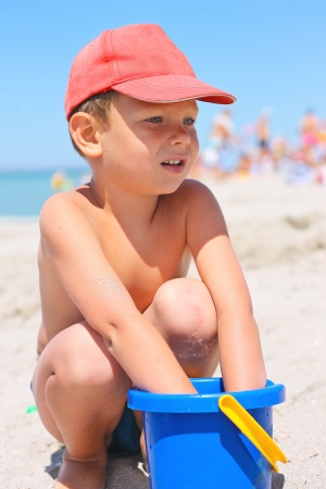 Cute little boy with a bucket on the beach by the seaの写真素材