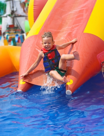 Enthusiastic kid on slide in the waterparkの写真素材