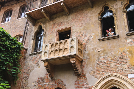 VERONA, ITALY - MAY 7, 2014: Girl photographs on their smartphone from a window in the museum courtyard Juliet. Verona, Italyのeditorial素材