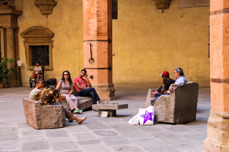 Bologna, Italy - August 18, 2014: People resting on a stone bench in the courtyard of the Palazzo Comunale in Bologna. Italyのeditorial素材