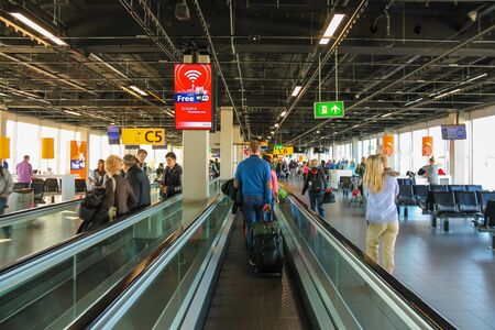 Amsterdam Schiphol, Netherlands - April 18, 2015: Interior of Amsterdam Airport Schiphol. Passengers on a long horizontal escalatorのeditorial素材