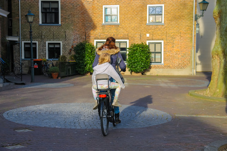 Meerkerk, municipality Zederik, Netherlands - April 13, 2015: The woman and little girl riding a bicycle in the Dutch city Meerkerk, Netherlandsのeditorial素材