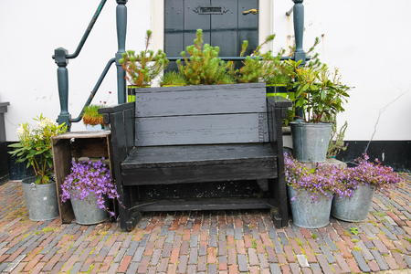 Traditional Dutch wooden bench surrounded by decorative plants on the city streetの写真素材