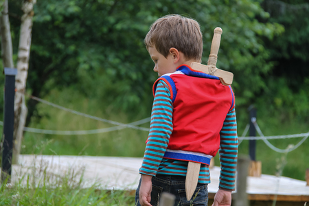 Boy with wooden sword in summer forest parkの写真素材
