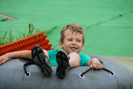 Smiling boy slides down in inflatable ringの写真素材