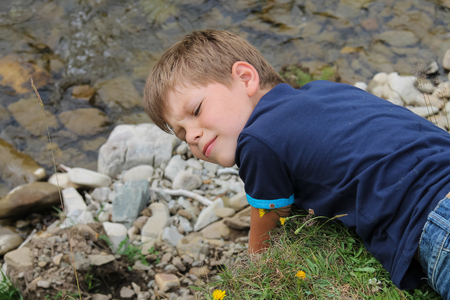 Boy lies near mountain river in Carpathians, Ukraineの写真素材