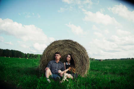 lovers resting in a field near haystacks.Outdoor portraitの写真素材
