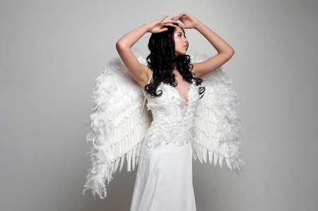 Sweet girl with a beautiful face in the form of an angel posing on gray background.Isolated studio portraitの写真素材