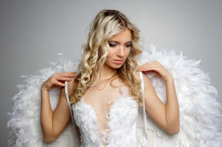 Sweet girl with a beautiful face in the form of an angel posing on gray background.Isolated studio...