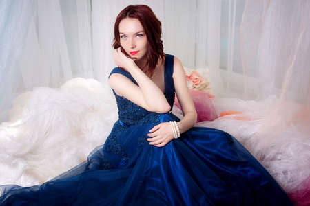 Beautiful young girl in evening dress posing at interior photo studio.Isolated portrait
