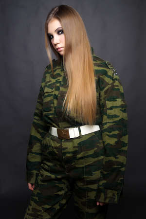 A girl soldier in camouflage clothing poses in a Studio.Indoor portraitの写真素材