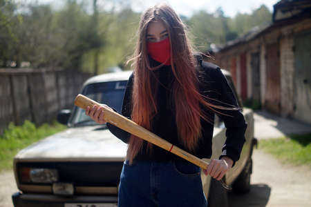 a young girl with a bat is standing near the car.Outdoor portrait
