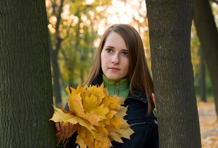 autumn girl portrait outdoors with golden tree leavesの写真素材