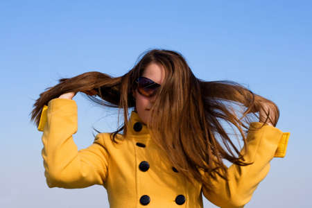 portrait of young girl in yellow with long hair over blue skyの写真素材