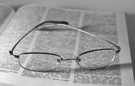 Monochrome image of glasses on an open book
