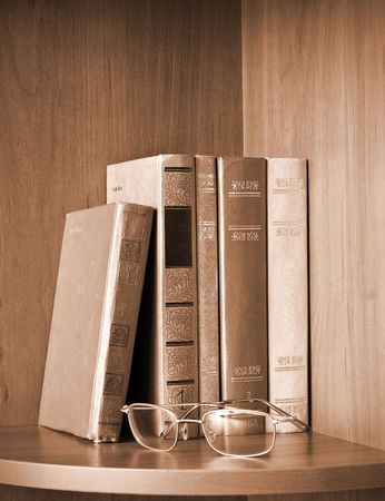 Vintage photo of old books and glasses on a shelfの写真素材