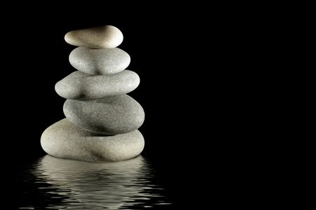 stack of balanced zen stones reflecting on water