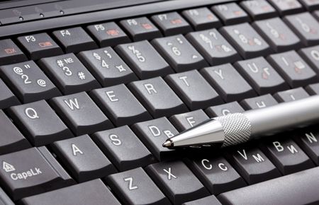 Black laptop and silver penの写真素材