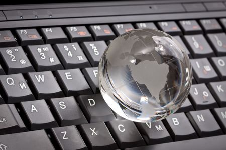 white glass globe on a laptop keyboardの写真素材