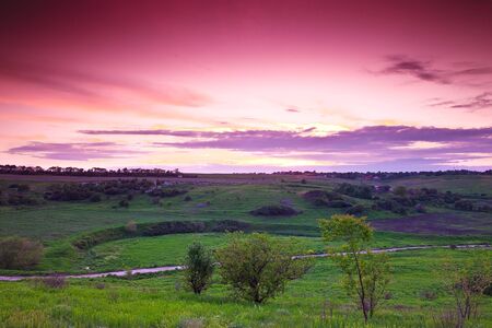 landscape of green fields in summer at sunsetの写真素材
