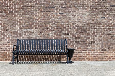 Park bench against a brick wallの写真素材
