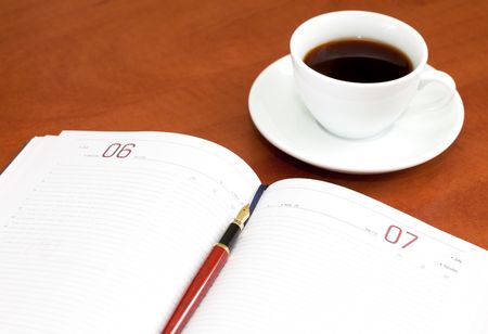 Coffee cup, notebook and pen on the wooden tableの写真素材