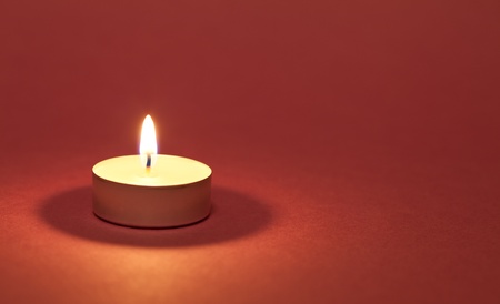 Burning candle on a red backgroundの写真素材