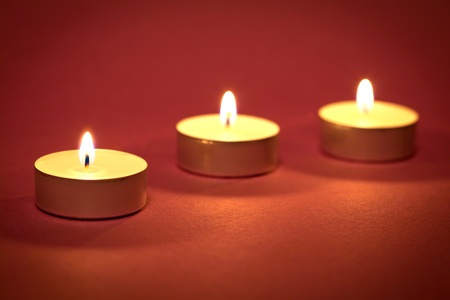Three candles on a red backgroundの写真素材