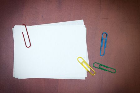 White paper note with a clips over the wooden background