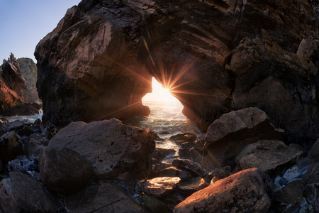 Sunset through rock arch, Ursa beach, Portugalの写真素材