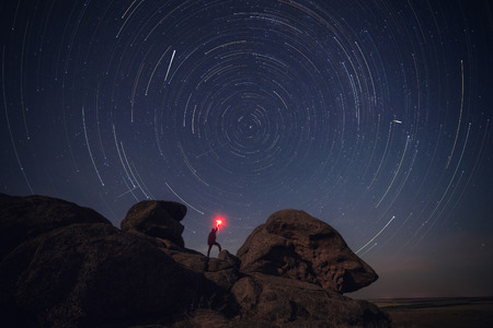 Rock and man silhouette over star tracksの写真素材
