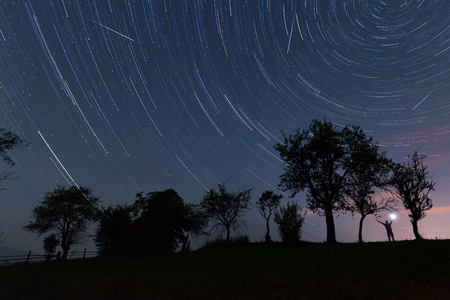 Trees and man silhouette over star tracksの写真素材