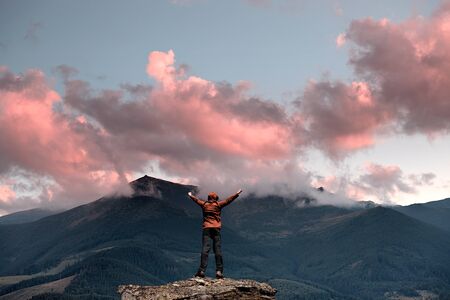 Man standing on the top of the mountain over sunset sky