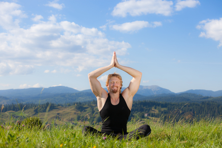Young man doing yoga exercise at the summer meadowの写真素材