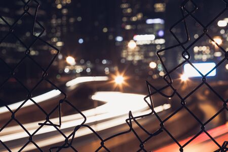 Nigh city bokeh lights through the wire mesh fenceの写真素材