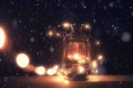 Vintage magic lantern with lights at snowy winter night