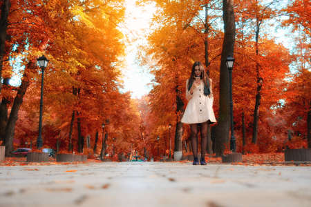 Beautiful girl holding smartphone city autumn parkの写真素材