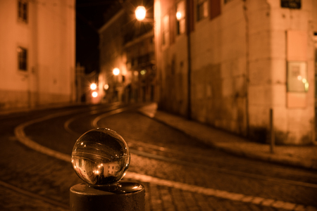 Illuminated street of old european town at night reflected in crystal globeの写真素材